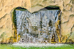 Small artificial waterfall in man made tropical garden. A small decorative waterfall in the garden. Landscape design