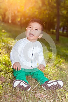 A small asian child plays in the Park sitting on the grass