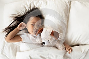 Small Asian girl sleep in bed with fluffy toy