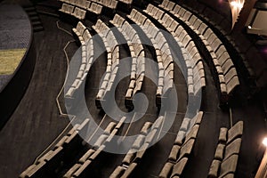 A small auditorium with rows of gray soft chairs, photo