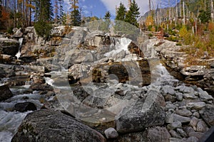 Small autumn Dlhy waterfall or wild stream in National Park High Tatras mountains, Slovakia. Hiking between colorful trees.