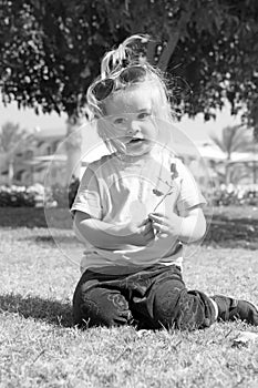 Small baby boy with adorable face on green grass