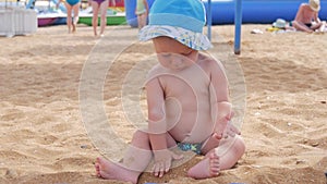 Small baby boy playing in the wet sand on the beach. He learns to crawl, waves embrace him.