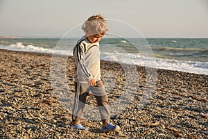 Small baby boy walking the seaside. the boy walks at sunset on the beach