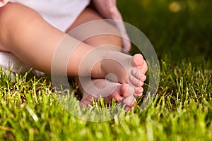 Small baby feet on the green grass at summer sunshiny day in the park. photo