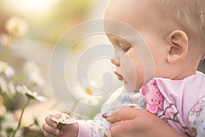 Small baby girl holding a daisy in her hand