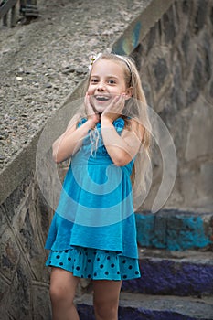 Small baby girl with surprised face in blue dress outdoor