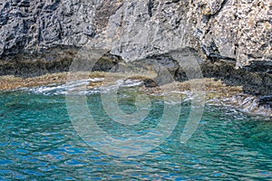 Small backwater surrounded by a stone cliff with azure water in Cyprus