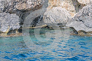 Small backwater surrounded by a stone cliff with azure water in Cyprus