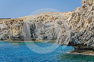 Small backwater surrounded by a stone cliff with azure water in Cyprus