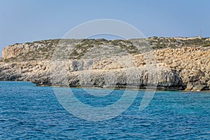 Small backwater surrounded by a stone cliff with azure water in Cyprus