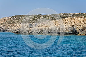 Small backwater surrounded by a stone cliff with azure water in Cyprus