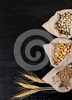 Small bags with various grains and cereals on wooden table, top view, copy space