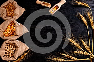 Small bags with various grains and cereals on wooden table, top view, copy space