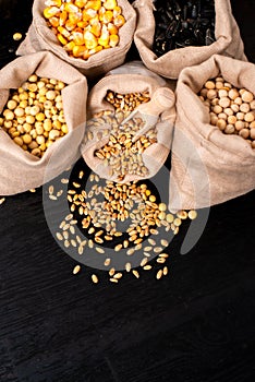 Small bags with various grains and cereals on wooden table, top view, copy space