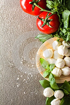 Small balls of mozzarella with basil leaves and olive oil on rustic background