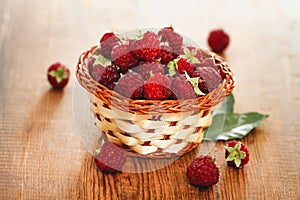 Small basket with ripe raspberry on wooden table