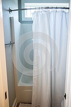 a small bathroom with a bathtub shower insert with a hanging white shower curtain