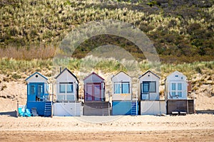 Small beach huts on white sandy North sea beach near Zoutelande, Zeeland, Netherlands photo