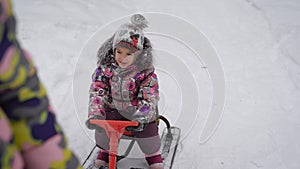 Small beautiful baby sitting on new sledding. His mother takes him through the snow, in order to then rolled off the