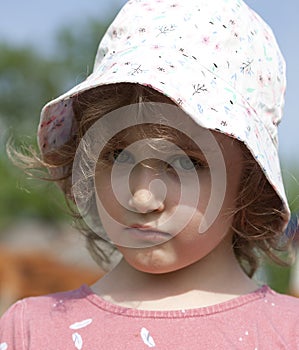 A small beautiful curly-haired girl looks sad and offended. Panama, curls, outdoors