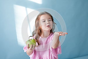 Small beautiful girl eating Apple green teeth