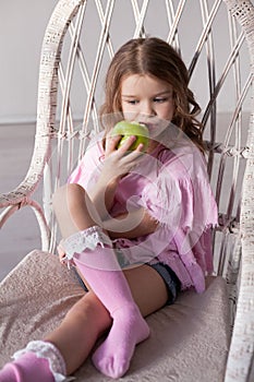 Small beautiful girl eating Apple green teeth