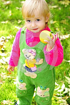 Small beautiful girl on green herb by autumn