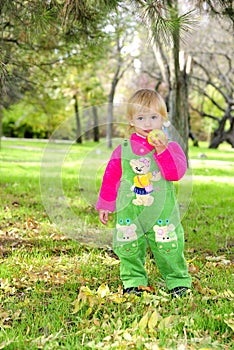 Small beautiful girl on green herb by autumn