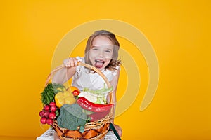 Small beautiful girl holding a basket of fresh fruit and vegetables healthy food