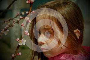 A small, beautiful girl in pink clothes walking in the Park near a flowering tree