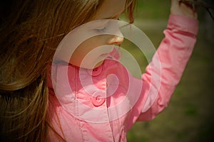 A small, beautiful girl in pink clothes walking in the Park near a flowering tree