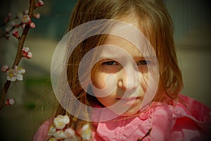 A small, beautiful girl in pink clothes walking in the Park near a flowering tree