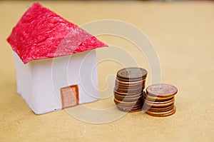 Small beautiful house with coins stacked in front of the housing model pretending: house prices, house buying, real