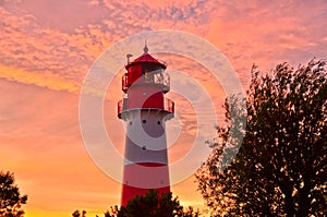 A small and beautiful lighthouse in the evening dawn sunset with pink clouds and bright light in FalshÃÂ¶ft, Germany photo