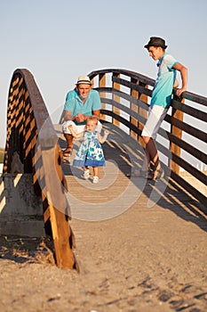 Small beautiful pretty girl is walking on wooden bridge to his father.