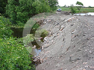 A small beautiful river is overburdened with soil and broken brick