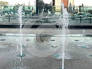 A small beautiful singing fountain in the open air, on the street. Drops of water, jets of water frozen in the air in flight again