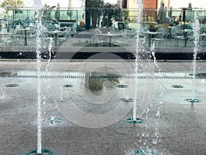 A small beautiful singing fountain in the open air, on the street. Drops of water, jets of water frozen in the air in flight again