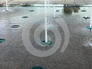 A small beautiful singing fountain in the open air, on the street. Drops of water, jets of water frozen in the air in flight again