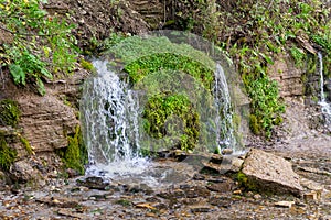 A small beautiful waterfall on a hillside in the forest.