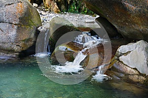 Small beautiful waterfall among the rocks of mountain creek