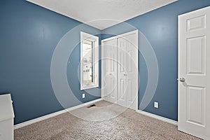 Small bedroom with a blue wall and white door