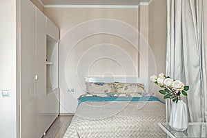 Small beige bedroom with bed and wardrobe