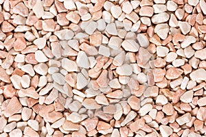 Small beige color round pebbles gravel background texture.