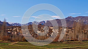 Small Berber village located in Atlas Mountains near Imilchil, Morocco, Africa with green fields and snow-capped mountains.