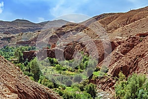 Small Berber village located in a green oasis valley with fields and palm trees , Morocco in the Atlas Mountains