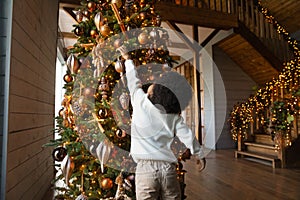 Small biracial boy decorate Christmas fir tree