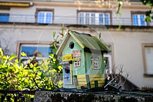 Small bird house on a stone fence with funny inscription