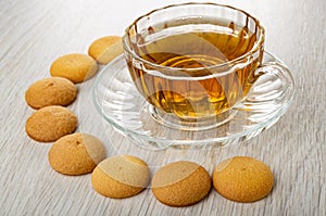 Small biscuits around cup with tea on wooden table